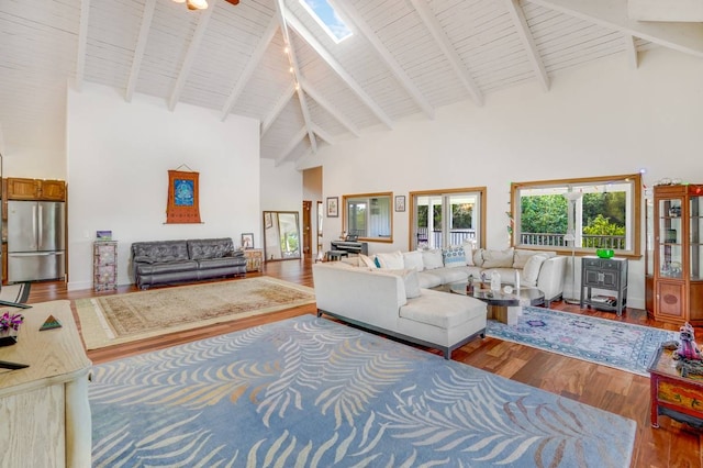 living room with a skylight, ceiling fan, beamed ceiling, high vaulted ceiling, and hardwood / wood-style flooring