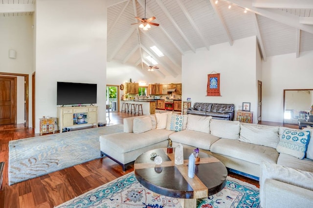 living room with beamed ceiling, ceiling fan, wood-type flooring, and high vaulted ceiling