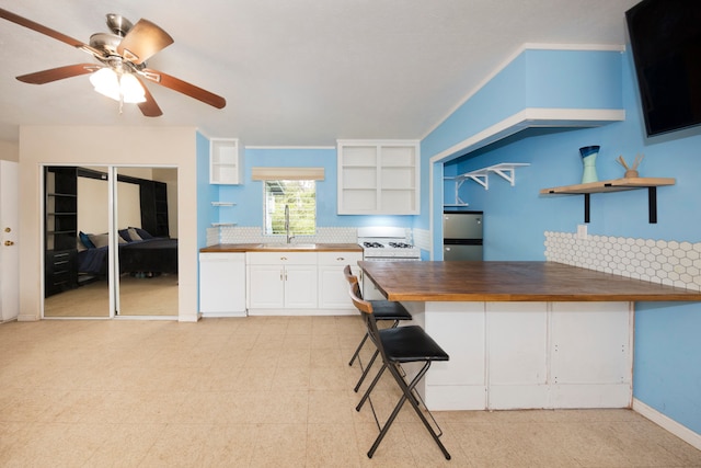 kitchen with sink, butcher block countertops, white appliances, a breakfast bar, and white cabinets