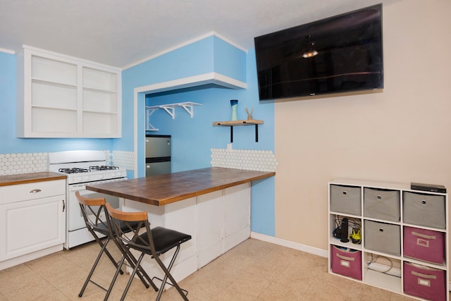 kitchen featuring wooden counters, stainless steel fridge, crown molding, white cabinets, and white gas range oven