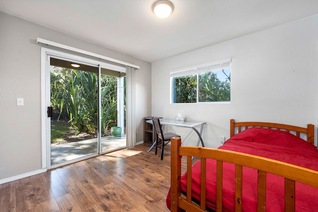 bedroom with access to exterior, hardwood / wood-style floors, and multiple windows