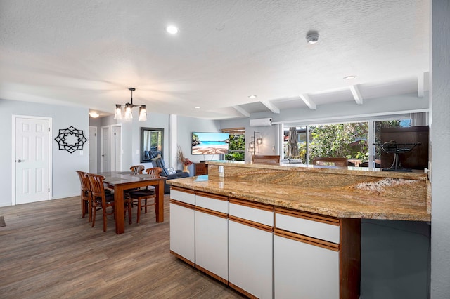 kitchen featuring beam ceiling, hanging light fixtures, hardwood / wood-style floors, a chandelier, and white cabinets