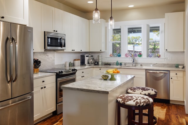 kitchen featuring dark wood-type flooring, white cabinets, sink, a kitchen island, and stainless steel appliances