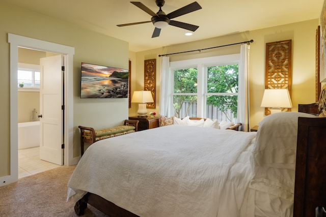 bedroom with light carpet, ensuite bath, and ceiling fan