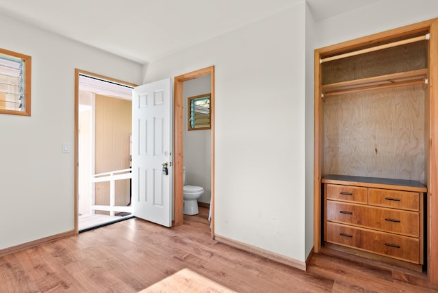 unfurnished bedroom featuring connected bathroom, a closet, and wood-type flooring