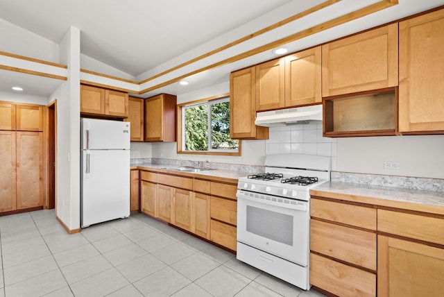 kitchen with light tile patterned flooring, white appliances, sink, and vaulted ceiling