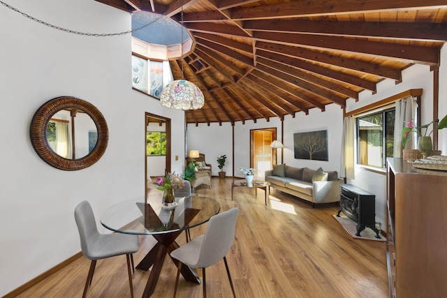 dining area with wood ceiling, beamed ceiling, a wood stove, high vaulted ceiling, and hardwood / wood-style flooring