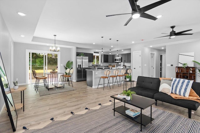 living room featuring light hardwood / wood-style flooring and ceiling fan with notable chandelier