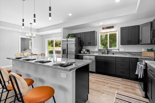 kitchen featuring sink, a kitchen breakfast bar, pendant lighting, a kitchen island with sink, and appliances with stainless steel finishes