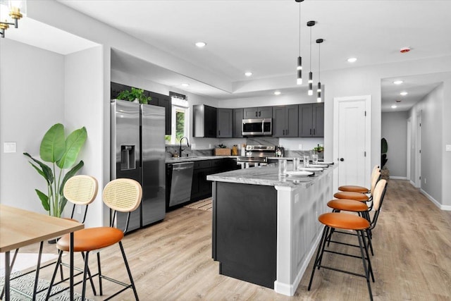 kitchen with sink, light hardwood / wood-style flooring, pendant lighting, and appliances with stainless steel finishes