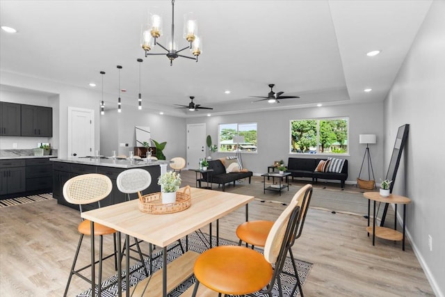 dining room with ceiling fan with notable chandelier and light hardwood / wood-style flooring