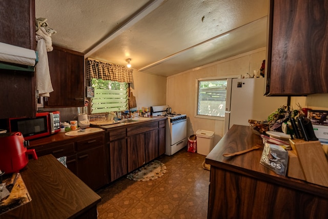 kitchen with lofted ceiling, dark brown cabinets, white appliances, and a textured ceiling