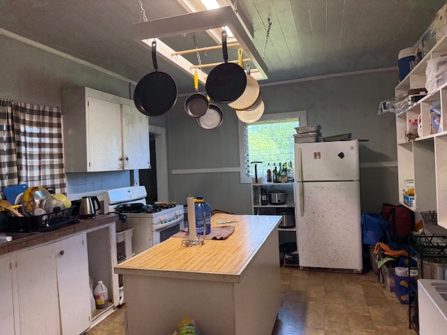 kitchen with white cabinetry, a center island, white appliances, and ornamental molding