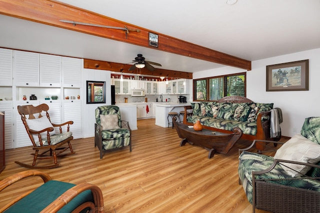 living room with beam ceiling, ceiling fan, light hardwood / wood-style flooring, and sink