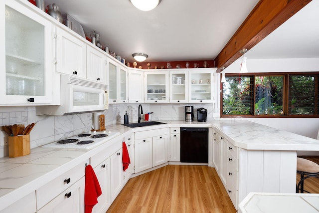 kitchen with a breakfast bar, white appliances, white cabinets, sink, and decorative backsplash