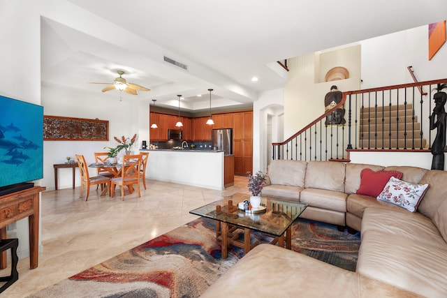 living room featuring ceiling fan and a tray ceiling