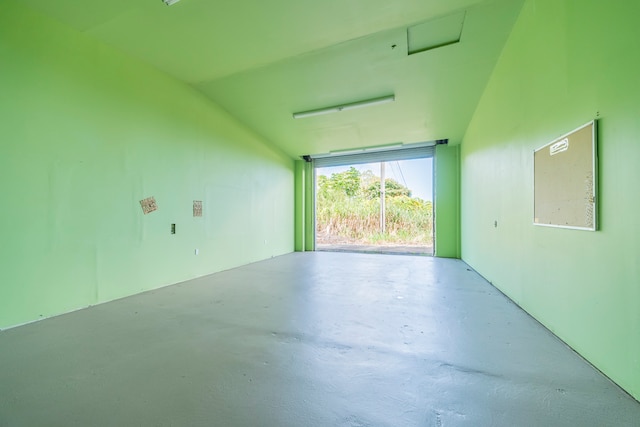 spare room featuring concrete flooring and vaulted ceiling