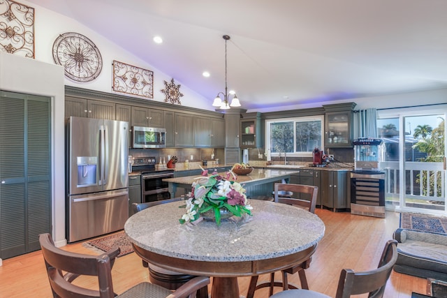 kitchen featuring beverage cooler, stainless steel appliances, backsplash, pendant lighting, and light hardwood / wood-style floors