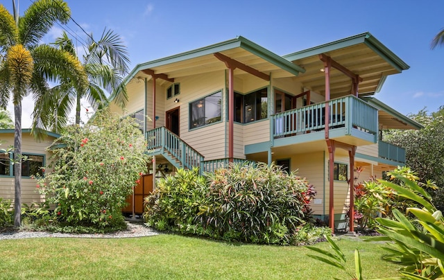 rear view of house featuring a balcony and a yard