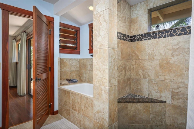 bathroom with wood-type flooring, vaulted ceiling, and tiled tub