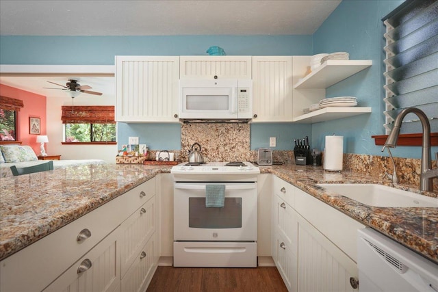 kitchen with white appliances, sink, dark hardwood / wood-style floors, ceiling fan, and light stone countertops