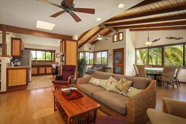 living room with ceiling fan, light hardwood / wood-style floors, lofted ceiling with skylight, and wood ceiling