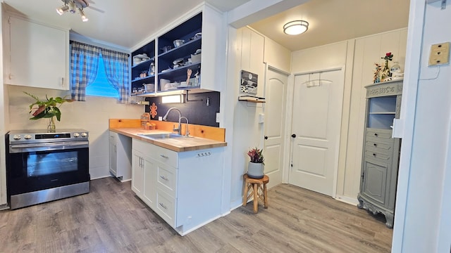 kitchen featuring white cabinetry, sink, butcher block countertops, stainless steel range with electric cooktop, and light wood-type flooring