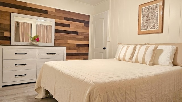 bedroom with wood walls and light hardwood / wood-style floors