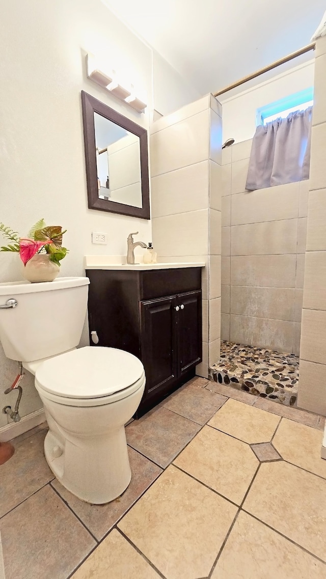 bathroom with tile patterned flooring, toilet, vanity, and tiled shower