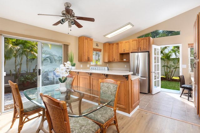 kitchen with lofted ceiling, a healthy amount of sunlight, stainless steel refrigerator, and kitchen peninsula