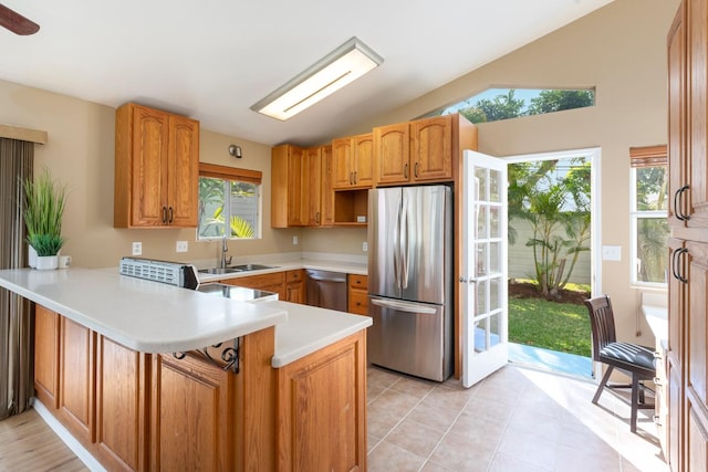 kitchen featuring vaulted ceiling, sink, light tile patterned floors, kitchen peninsula, and stainless steel appliances