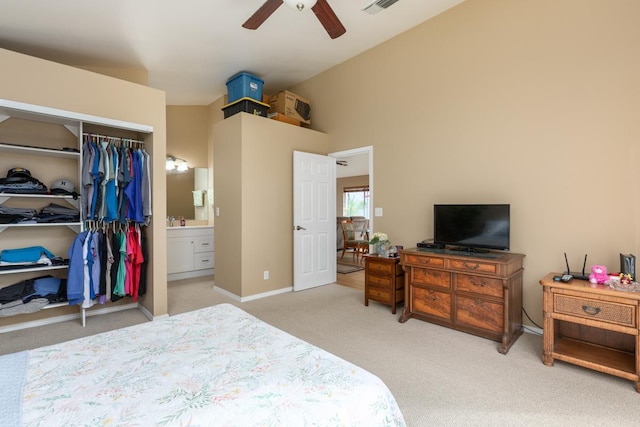 bedroom with ceiling fan, connected bathroom, light carpet, vaulted ceiling, and a closet