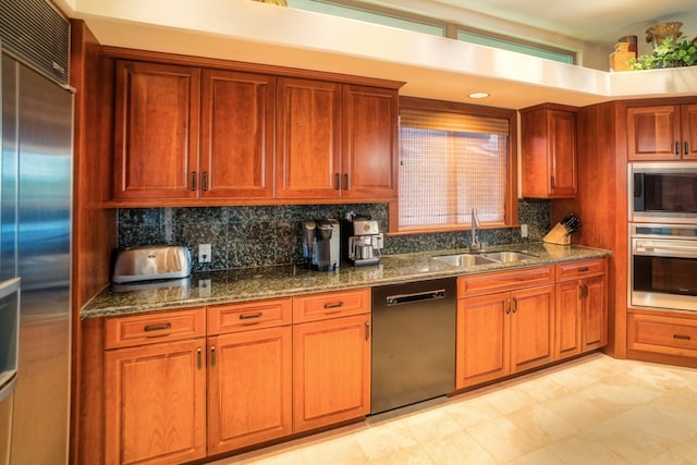 kitchen with built in appliances, backsplash, dark stone counters, and sink