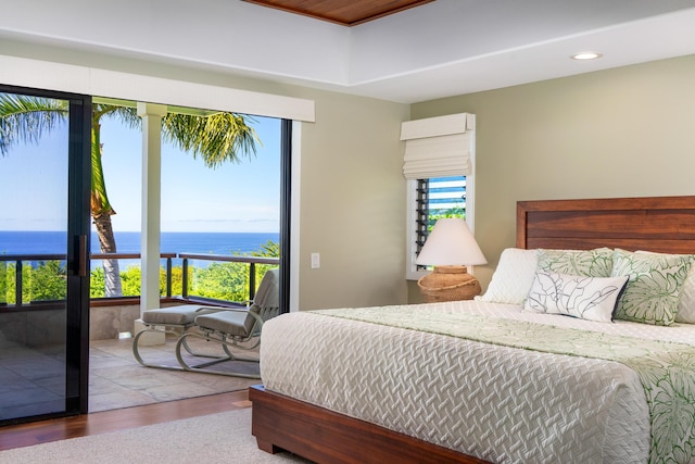 bedroom featuring a water view, wood-type flooring, access to outside, and multiple windows