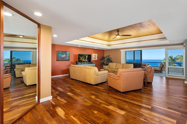 living room featuring a tray ceiling, dark hardwood / wood-style floors, and ceiling fan