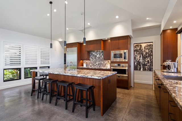 kitchen with sink, decorative backsplash, an island with sink, appliances with stainless steel finishes, and decorative light fixtures