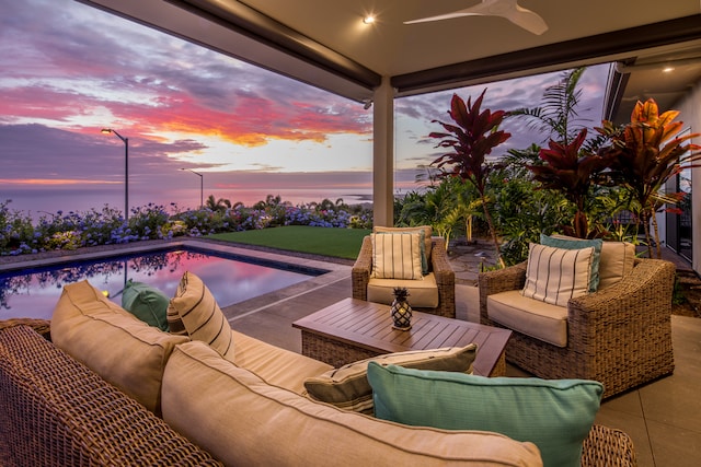 pool at dusk with ceiling fan and a patio