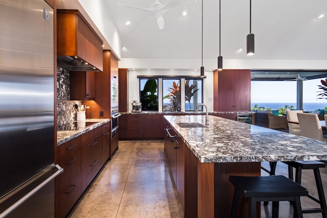 kitchen with sink, stainless steel appliances, tasteful backsplash, an island with sink, and decorative light fixtures