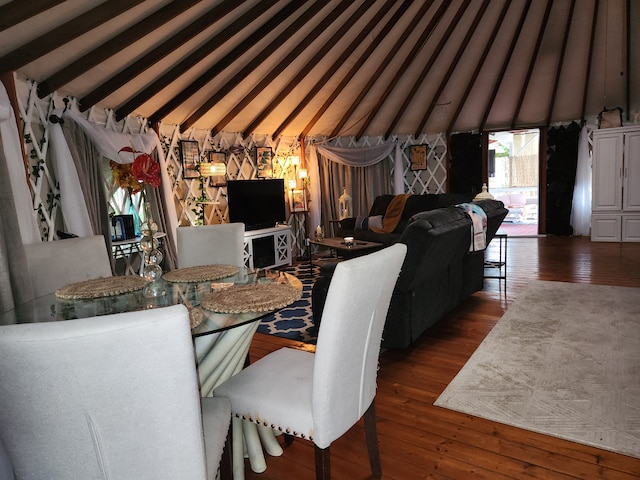 dining room with dark wood-type flooring and vaulted ceiling