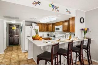 kitchen featuring a kitchen breakfast bar, white appliances, and kitchen peninsula