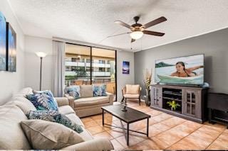 living room with ceiling fan, tile patterned flooring, and a textured ceiling