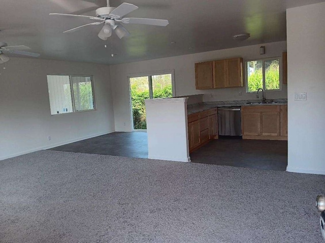 kitchen featuring dark colored carpet, dishwasher, sink, and a wealth of natural light