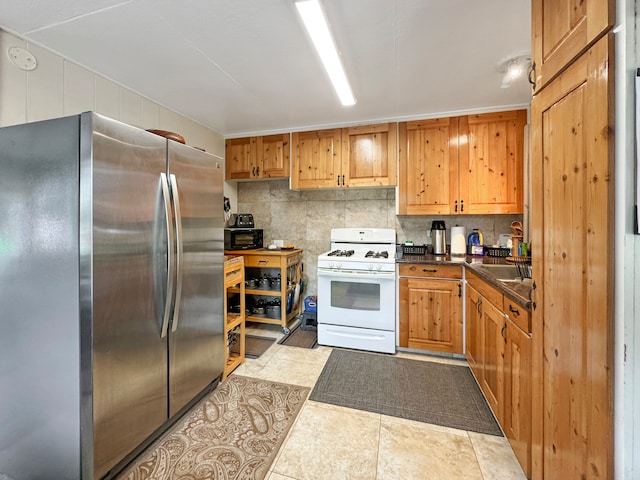 kitchen featuring stainless steel fridge, white gas range oven, tasteful backsplash, and light tile patterned floors