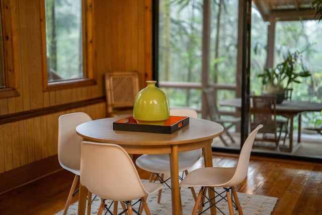 dining area featuring wood-type flooring and wooden walls