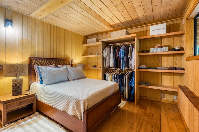 bedroom with hardwood / wood-style floors, wood ceiling, wooden walls, and a closet