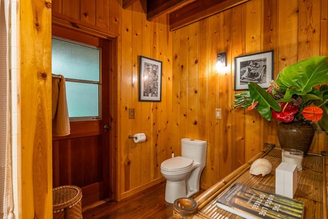 bathroom with beamed ceiling, hardwood / wood-style floors, toilet, and wooden walls