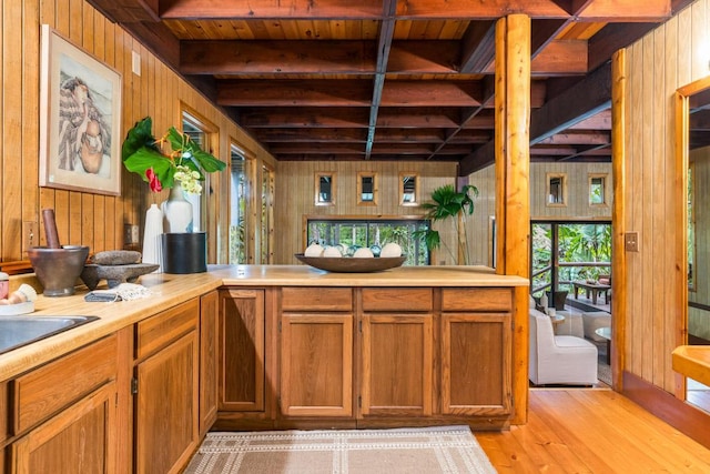 kitchen featuring beam ceiling, a wealth of natural light, and wood walls