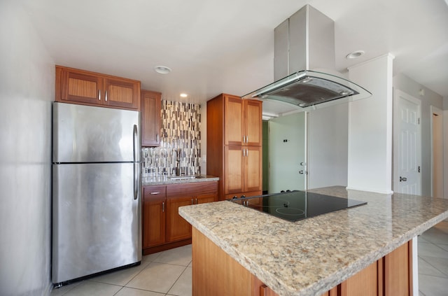 kitchen with light tile patterned flooring, sink, black electric cooktop, stainless steel fridge, and island exhaust hood