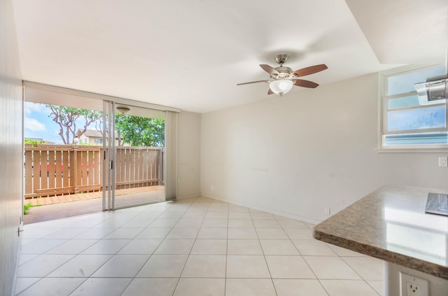 tiled spare room with floor to ceiling windows and ceiling fan