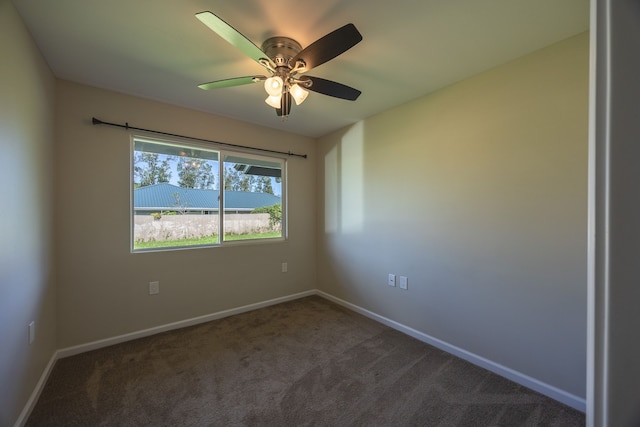 spare room featuring ceiling fan and dark carpet